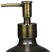 Load image into Gallery viewer, Close-up of a dark smoky glass bottle with a brushed brass or antique gold pump dispenser against a solid black background.