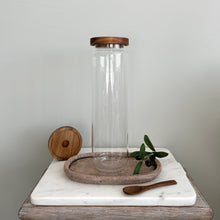 Load image into Gallery viewer, Clear glass jar with wooden lid on a marble surface against a plain background