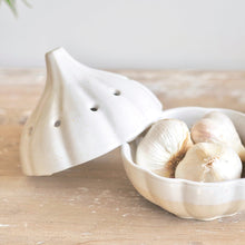 Load image into Gallery viewer, White ceramic garlic canister holder on a wooden surface with with garlic cloves inside