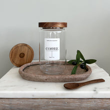 Load image into Gallery viewer, Glass jar with a acacia wooden airtight lid with white waterproof lablel, displayed on a stone tray with a wooden spoon and greenery.