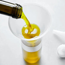 Load image into Gallery viewer, Oil being poured from a bottle into a funnel on a white background