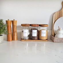 Load image into Gallery viewer, A medium glass jar with an Acacia wood lid, part of a set displayed on a kitchen counter along with other items.