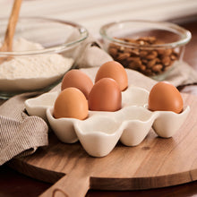 Load image into Gallery viewer, Eggs in a white ceramic tray on a wooden surface with a blurred  background
