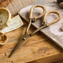 Load image into Gallery viewer, Brass scissors with hand-wrapped rattan handles resting on a rustic wooden surface — elegant artisan tool for desk, craft, or utility room decor.
